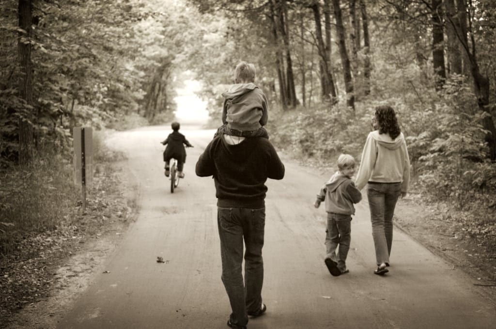 family walking on a road at a Minnesota lake resort, with one child biking