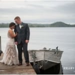 Bride and Groom standing on pier by boat on cloudy day
