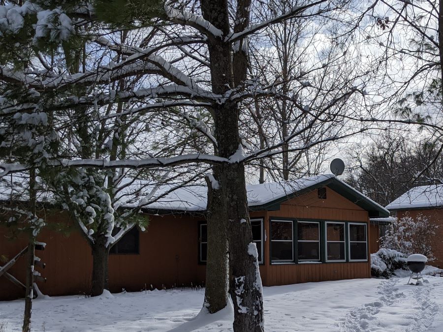 Lakeside cabin covered with snow by snow covered trees and lawn near Brainerd, MN, a great place to host the holidays