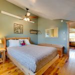 A queen bed, hardwood floors, natural lighting, and ceiling fan in a 4br resort rental cabin