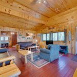 Rustic cabin living area with two futons and a chair, tv and fireplace