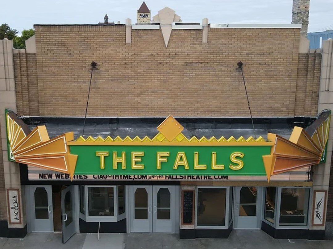 Exterior of old movie theater with bright green marquee that says "The Falls"