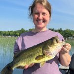 Young woman holds a big largemouth bass while on a boat