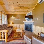 Lakeside rental living room with fireplace, satellite TV above the fireplace, pine futon, leather armchair and view of Lake