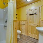 yellow and pine bathroom with sink, stool, shower