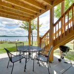 Exterior of cabin with patio sitting area, stairs to the upstairs patio, and a beautiful lake view