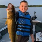 Boy holds a walleye fish on a boat on Fish Trap Lake