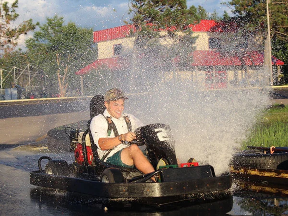 Man go carting on a tar track gets splashed with water