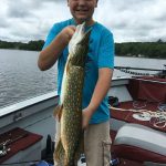 boy holds a large northern pike vertically