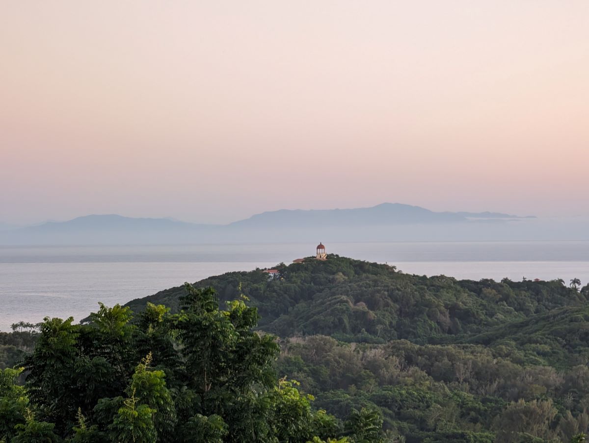 A tower sits atop a hill overlooking the sea and mountains far away at sunset reminds us to visualize the future and to create goalposts along our roadmap to goal acheivement.