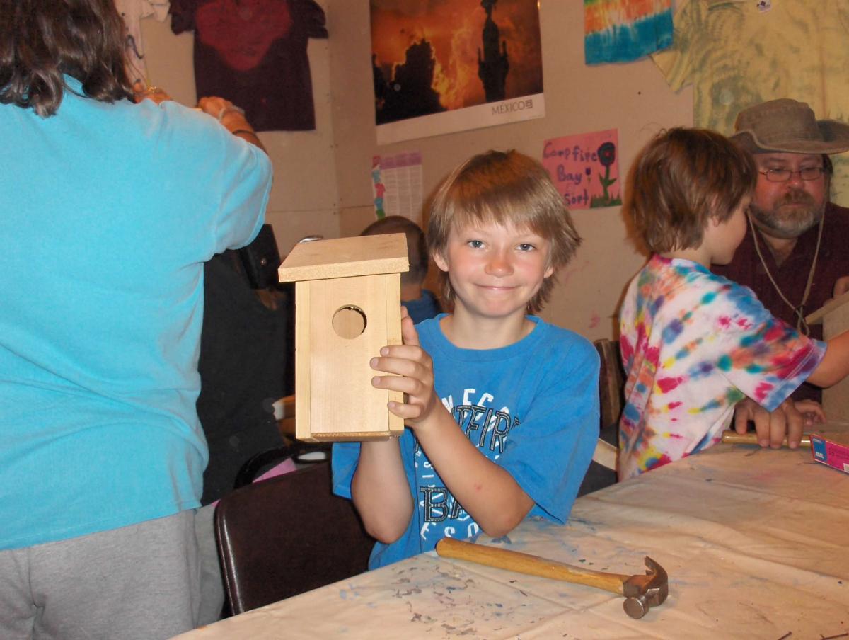 Boy holds up a wood birdhouse he's made as part of a Minnesota resort organized activities, a goal met along our roadmap to goal achievement 