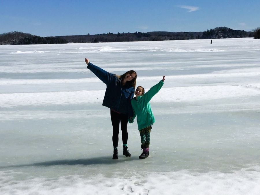 A teenager and her little sister play on frozen Fish Trap Lake during spring break at an up north lakeside resort rental cabin