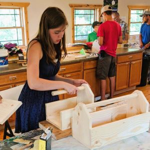 Younge women, like this gal, kids, and people of all ages love woodworking activity at Campfire Bay Resort