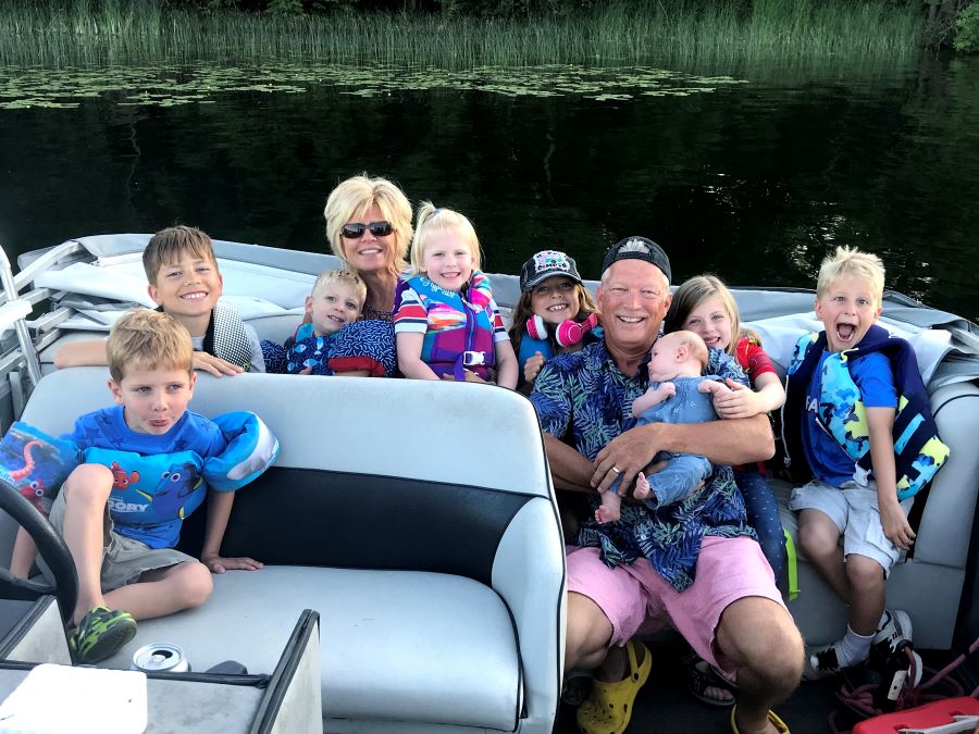 Grandparents and several grandchildren smile and cuddle on their boat on Fish Trap Lake, MN