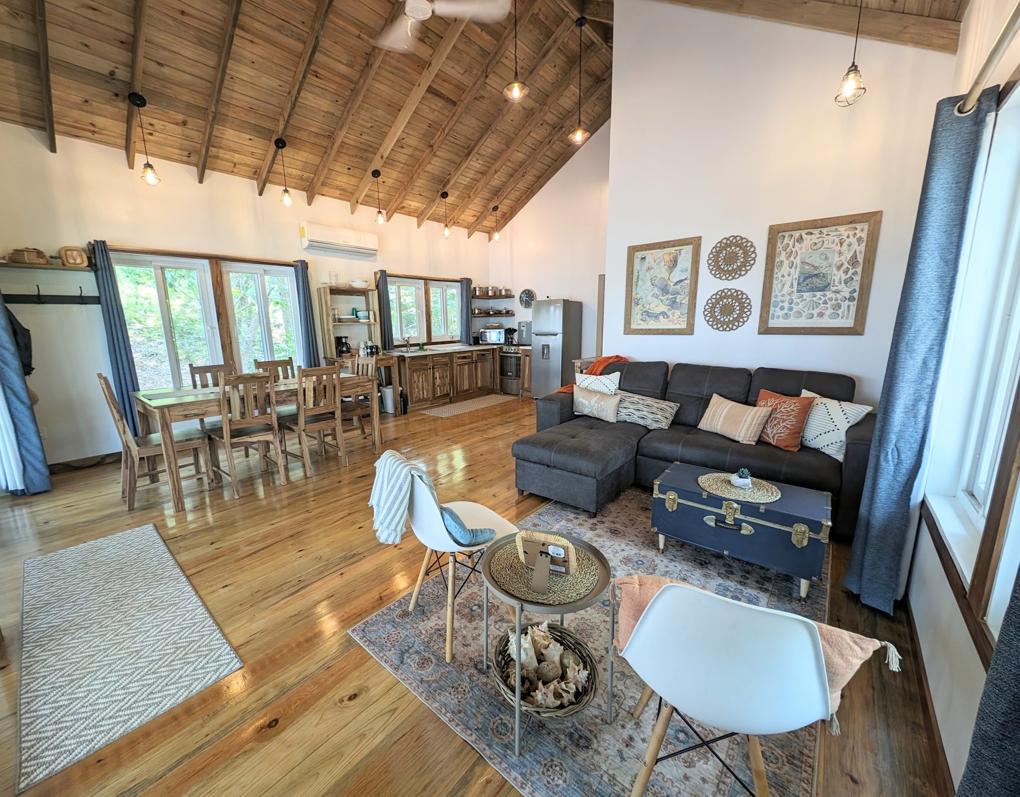 Tropical island rental cabin living area has a sleeper sofa, side chairs, a dining set that seats 6, and a full kitchen