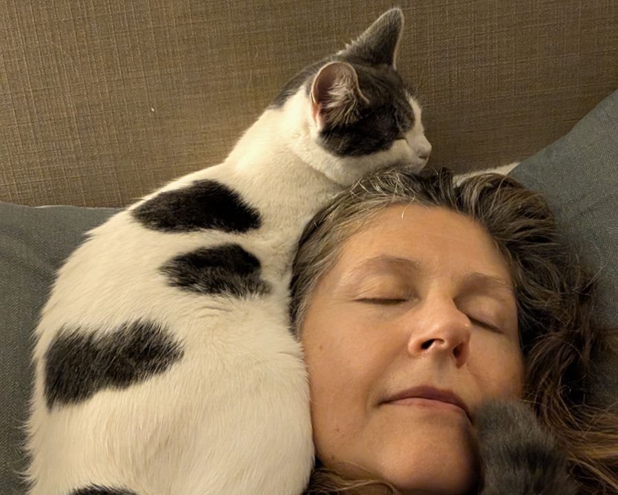 A black and white cat sleeps on a woman's head
