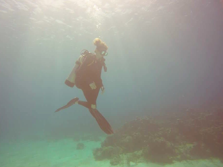 A woman diver is suspended about coral and sand near Morada Coralina, a rental on Roatán 