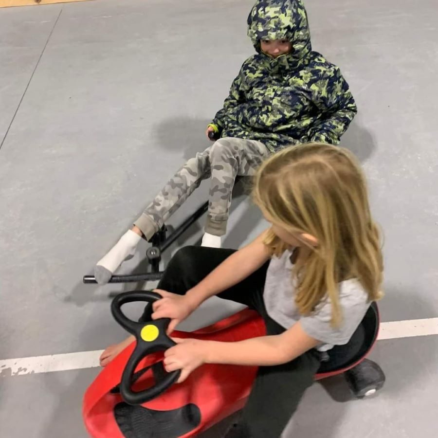 Two kids ride little scooters in the gym at MN resort